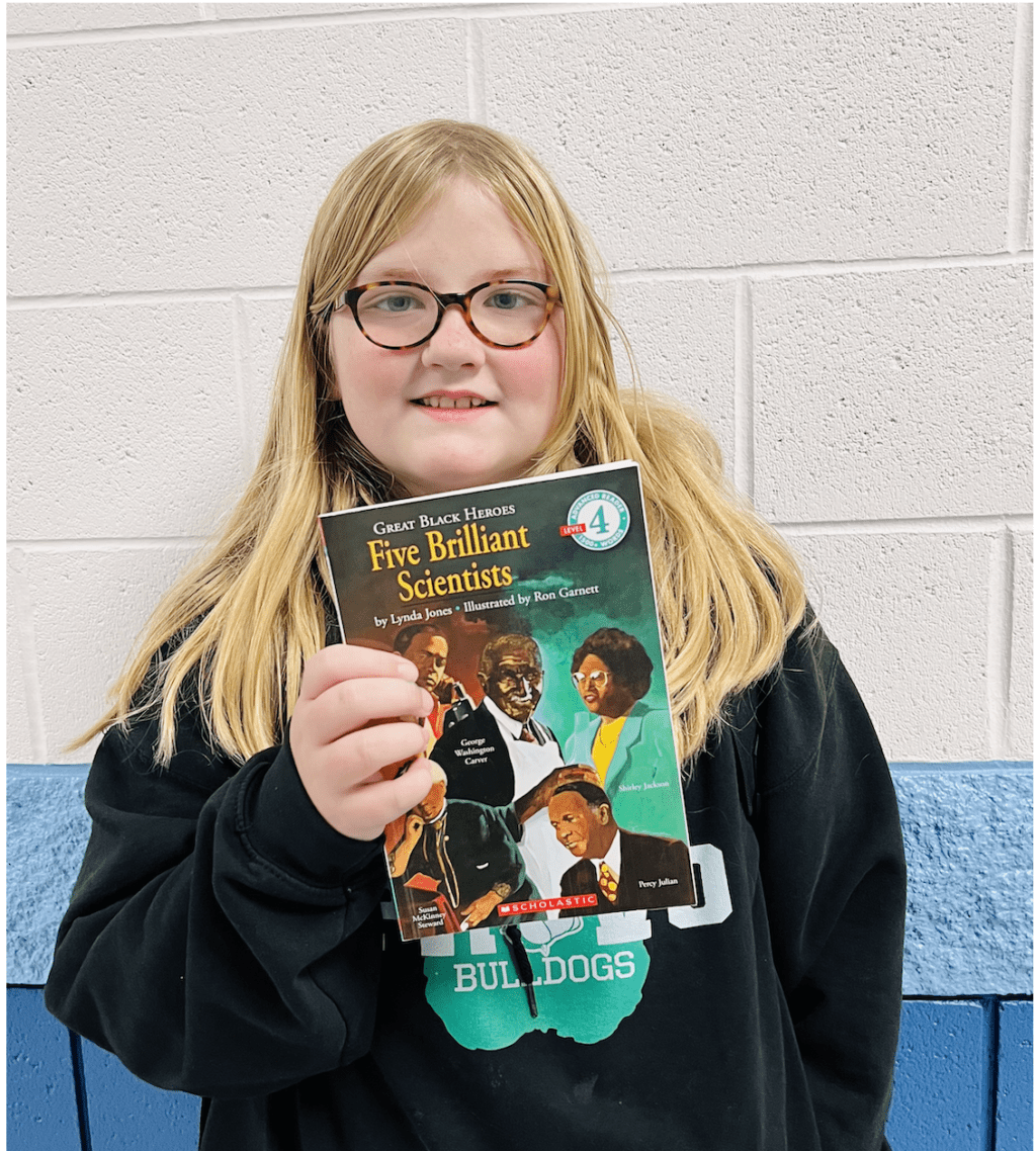 student holding a book received for earning a  praise award